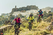 Drei Mountainbiker auf Patmos vor der Kulisse des Klosters des Heiligen Johannes.