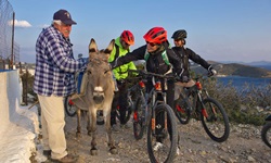 Eine Gruppe Mountainbiker auf Patmos streichelt einen Esel und plaudert mit dessen Besitzer.