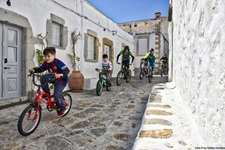 Eine Familie mit drei Erwachsenen und zwei Kindern bikt durch einen Ort auf der Insel Patmos.