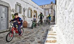 Eine Familie mit drei Erwachsenen und zwei Kindern bikt durch einen Ort auf der Insel Patmos.