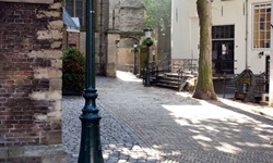Eine Gasse in Gouda mit eine alten Straßenaterne, die mit Blumen geschückt ist