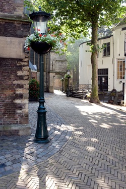 Eine Gasse in Gouda mit eine alten Straßenaterne, die mit Blumen geschückt ist