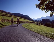Zwei Radfahrer auf der Graubünden-Route genießen den Ausblick auf die vor ihnen liegenden, majestätischen Berggipfel.