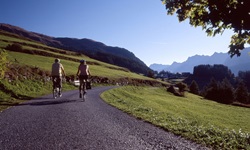 Zwei Radfahrer auf der Graubünden-Route genießen den Ausblick auf die vor ihnen liegenden, majestätischen Berggipfel.