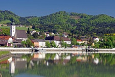 Die Pfarrkirche von Grein, dem Hauptort des Strudengaus, und die sie umgebenden Häuser spiegeln sich im Wasser der Donau.
