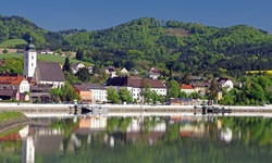 Die Pfarrkirche von Grein, dem Hauptort des Strudengaus, und die sie umgebenden Häuser spiegeln sich im Wasser der Donau.