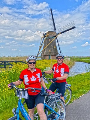 Ein Radlerpaar auf einem Radweg in der Nähe von Schermerhorn posiert vor einer Windmühle