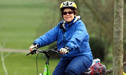 Eine Radlerin auf einem neongrünen Fahrrad schaut fröhlich in die Kamera.