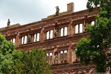 Die mit vielen Statuen verzierte Fassade des Heidelberger Schlosses wird idyllisch von Bäumen umrahmt.