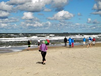 Eine Reisegruppe geht am Ostseestrand der Brandung entgegen.