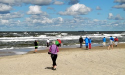 Eine Reisegruppe geht am Ostseestrand der Brandung entgegen.