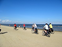 Eine Radlergruppe fährt am Ostseestrand entlang.