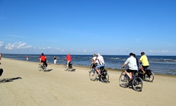 Eine Radlergruppe fährt am Ostseestrand entlang.