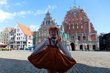 Ein kleines Mädchen in Tracht tanzt vor dem Rathaus von Riga.