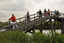 Eine Gruppe Radfahrer schiebt ihre Räder über eine Holzbrücke