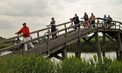 Eine Gruppe Radfahrer schiebt ihre Räder über eine Holzbrücke