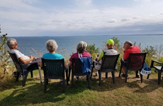 Fünf auf Stühlen sitzende Gäste genießen den Ausblick auf das Meer auf der Insel Rügen