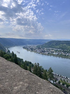 Blick von einem Aussichtspunkt über den mit einem Schiff befahrenen Lahn zu einer Stadt