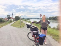 Eine Radlerin posiert auf dem Donauradweg neben ihrem vollgepackten Fahrrad