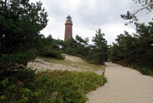 Ein Weg aus Sand, der zu einem Leuchtturm an der Ostsee führt