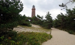 Ein Weg aus Sand, der zu einem Leuchtturm an der Ostsee führt