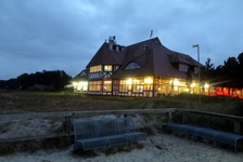Blick auf ein abendlich beleuchtetes Hotel und einem Sitzplatz am Strand der Ostsee