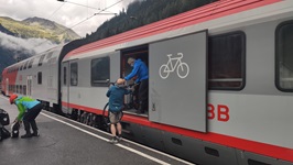 Gäste laden ein Fahrrad in den Fahrrad-Abteil eines Zuges in Salzburg ein