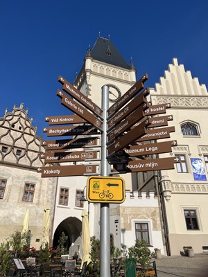 Ein Wegweiser mit zahlreichen braunen Schildern und einem gelben Radwegschild nach Wien in einer tschechischen Stadt