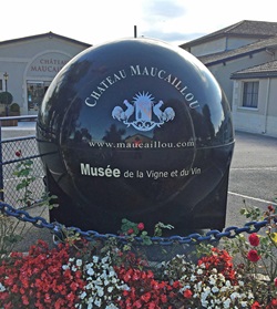 Eine schwarze Deko-Kugel mit weißer Aufschrift weist auf das Weingut Chateau Maucaillou und sein Weinmuseum hin.