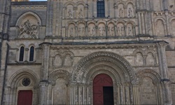 Drei Radlerinnen bestaunen die Fassade der Kirche Sainte-Croix in Bordeaux.