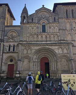 Drei Radlerinnen bestaunen die Fassade der Kirche Sainte-Croix in Bordeaux.