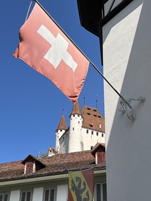 Blick auf eine Schweizer Flagge und eine Burg im Hintergrund auf der Alpenpanorama-Route in der Schweiz