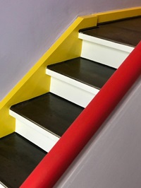 Detailbild einer gelb-schwarz-weiß-rot gestrichenen Holztreppe