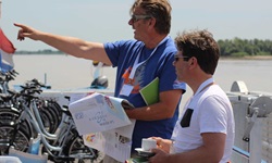 Einer der Reiseleiter auf der MS Bordeaux gibt einem Passagier anhand der Reiseunterlagen nützliche Tipps für die täglichen Radtouren.