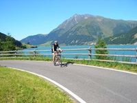 Ein Radfahrer fährt auf einem Radweg am Reschensee vorbei