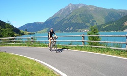 Ein Radfahrer fährt auf einem Radweg am Reschensee vorbei