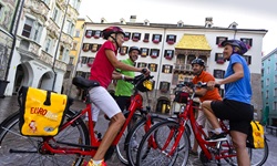 Vier Radfahrer beim Goldenen Dachl in der Innenstadt von Salzburg.