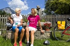 Zwei Radfarerinnen machen auf einer Bank in Tirol Pause.