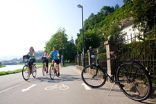 Drei Radlerinnen lassen auf einem asphaltierten Radweg Salzburg hinter sich.