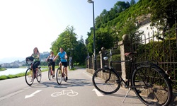 Drei Radlerinnen lassen auf einem asphaltierten Radweg Salzburg hinter sich.