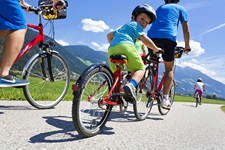 Eine Familie radelt auf einem asphaltierten Radweg durch Tirol.