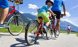 Eine Familie radelt auf einem asphaltierten Radweg durch Tirol.