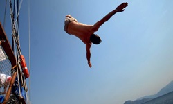 Ein Passagier macht einen Salto mit seinen Badesachen ins Meer