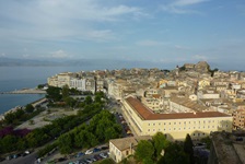 Blick auf die Stadt Korfu von der Neuen Festung aus. Im Vordergrund ist der Nahe am Meer gelegene Park mit Springbrunnen und im Hintergrund ist die Alte Festung zu sehen.