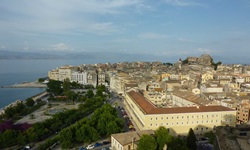 Blick auf die Stadt Korfu von der Neuen Festung aus. Im Vordergrund ist der Nahe am Meer gelegene Park mit Springbrunnen und im Hintergrund ist die Alte Festung zu sehen.