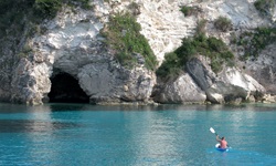 Ein Mann in einem Kanu auf dem Meer, der in Richtung einer Höhle der Ionischen Inseln paddelt