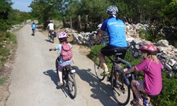 Eine Familie mit drei Kindern radelt eine schmale Straße auf der Inselhüpfen Erlebniskreuzfahrt auf den Ionischen Inseln entlang