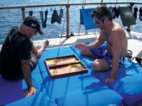 Zwei Passagiere spielen Backgammon auf den Liegematten am Sonnendeck