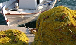Ein angelegtes Fischerboot im Golf von Korinth mit gelben Fangnetzen auf dem Steg