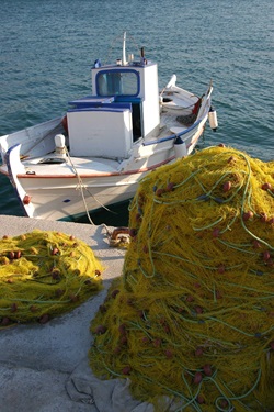 Ein angelegtes Fischerboot im Golf von Korinth mit gelben Fangnetzen auf dem Steg